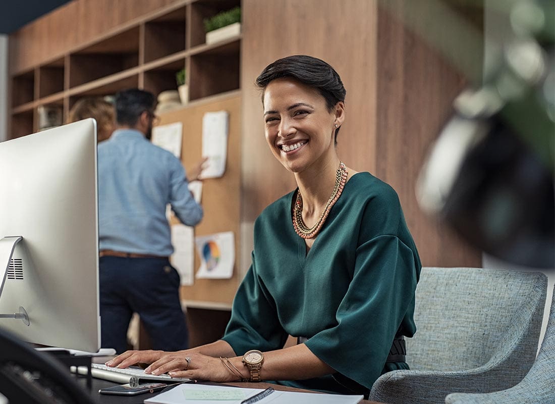 About Our Agency - Young Businesswoman Smiling at the Camera While in the Office