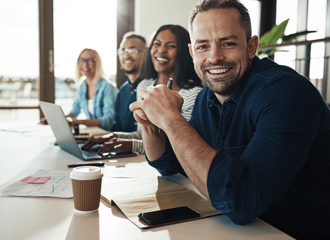 Business Insurance. - Smiling Businessman Sitting With Colleagues in the Office During a Meeting