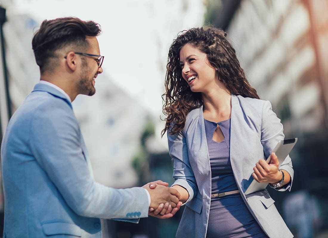 Insurance Solutions - Business Colleagues Shaking Hands and Smiling Outside of the Office on a Sunny Day