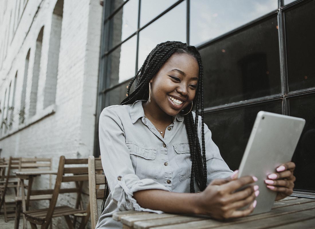 Read Our Reviews - Smiling Young Woman Sitting at a Table Outside of a Brewery